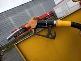 a person holding a gas nozzle in front of a yellow container