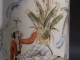 a white vase with a painting on it on a table