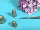 a bunch of thimbles and a needle on a blue surface