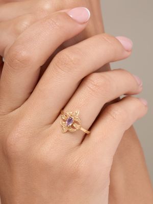 an image of a woman ' s hand with a gold ring with a purple stone
