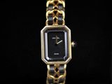 a close up of a gold and black watch on a black surface