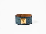 un bracelet en cuir bleu orné d'une pyramide en or