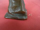 statue en bronze représentant une femme assise sur une surface rouge