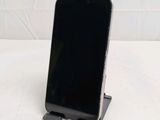 a black cell phone sitting on a stand on a table