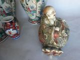 a statue of a man sitting on a plate next to vases