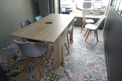 une table et des chaises en bois dans une pièce au sol carrelé