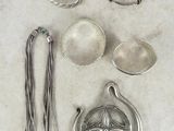 Plusieurs objets en argent sont disposés sur une surface blanche