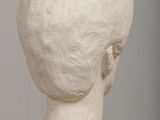 sculpture of a head on a wooden table with a gray background