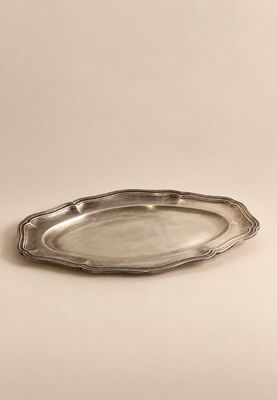 une assiette en argent posée sur une table, sur fond blanc