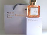 perfume bottle in a white box next to a white box with a black ribbon