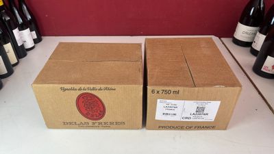 Deux caisses de vin sont posées sur un comptoir devant un mur rouge.