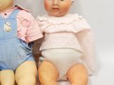 two dolls sitting next to each other on a white surface