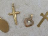 three gold crosses, a pearl pendant, and a cross on a white surface