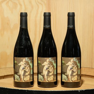 three bottles of wine sitting on top of a wooden barrel