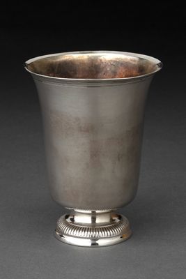 une coupe ancienne en argent posée sur un socle, sur fond noir