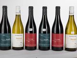 six bouteilles de vin sont alignées sur une table