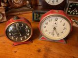 two clocks sitting on a wooden table next to each other