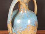 a blue and yellow vase sitting on a wooden table