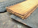 un vieux livre posé par terre à côté d'un objet en métal
