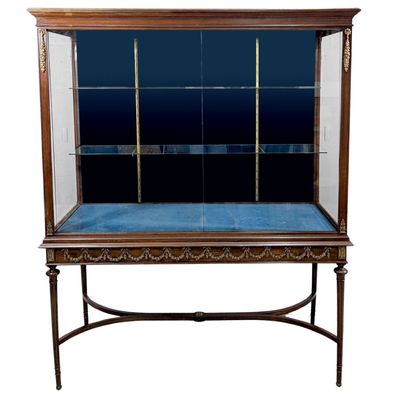 an antique display case with glass doors and a blue velvet cushion