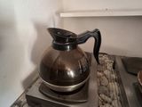 a coffee pot sitting on top of a stove next to a plate of food