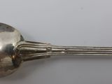 a silver spoon with a handle on a white surface