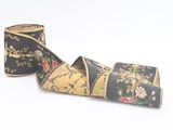 two rolls of black and gold floral ribbon on a white background