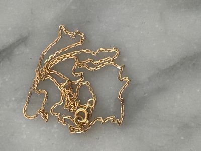 un collier plaqué or posé sur une surface en marbre