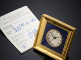 a small clock sitting next to a business card on a table