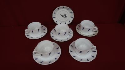 six cups and saucers are sitting on a red table cloth