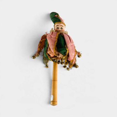 a small doll with a green hat and pink scarf on a stick