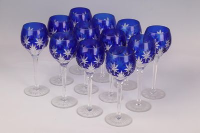 six blue wine glasses with white designs are lined up on a white surface