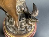 a bronze statue of a woman and a bird on a table