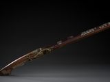 un fusil avec un canon en bois et des garnitures en laiton sur fond noir