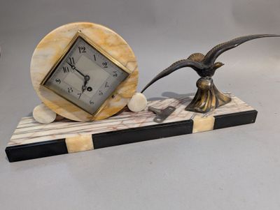 une horloge posée sur un socle orné d'un oiseau