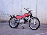 a red motorcycle parked in a parking lot next to a white wall