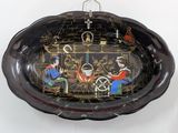 a black bowl with a painting on it hanging on a wall
