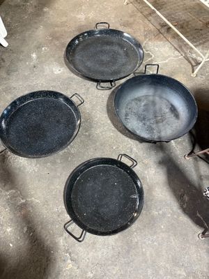 Plusieurs casseroles sont posées par terre à côté d'une cuisinière.