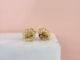 une paire de boucles d'oreilles en forme de fleurs en or posées sur un bloc de marbre