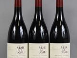 trois bouteilles de vin sont alignées sur une table