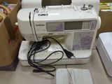 a white sewing machine sitting on a counter next to other sewing machines