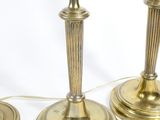 three brass candles are sitting on a white surface with a cord