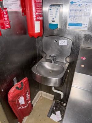 a sink and a fire extinguisher in a public restroom
