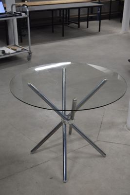 une table en verre avec un piètement en métal au milieu d'une pièce