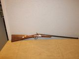 Le fusil est posé sur la table, près du mur.