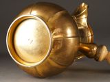 a gold vase with a wooden handle on a table