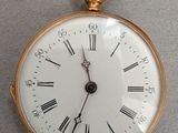 a gold pocket watch with roman numerals on the face