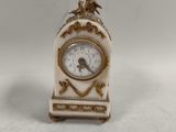 une petite horloge blanche surmontée d'un oiseau