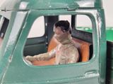 a green toy truck with a figurine of a man sitting in the driver ' s seat