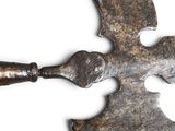 a large metal cross with a wooden handle on a white surface